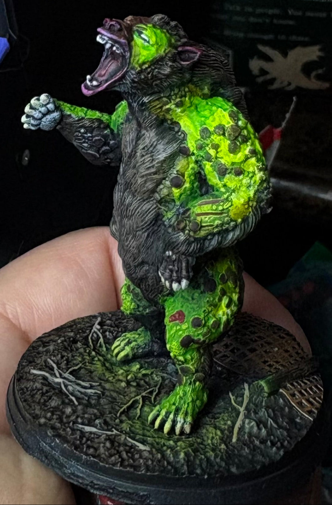 Green monster figurine held in a hand with a dark background